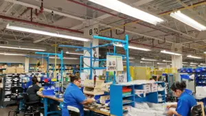 Personal de una empresa trabajando dentro de una fábrica debajo de luminarias inteligentes